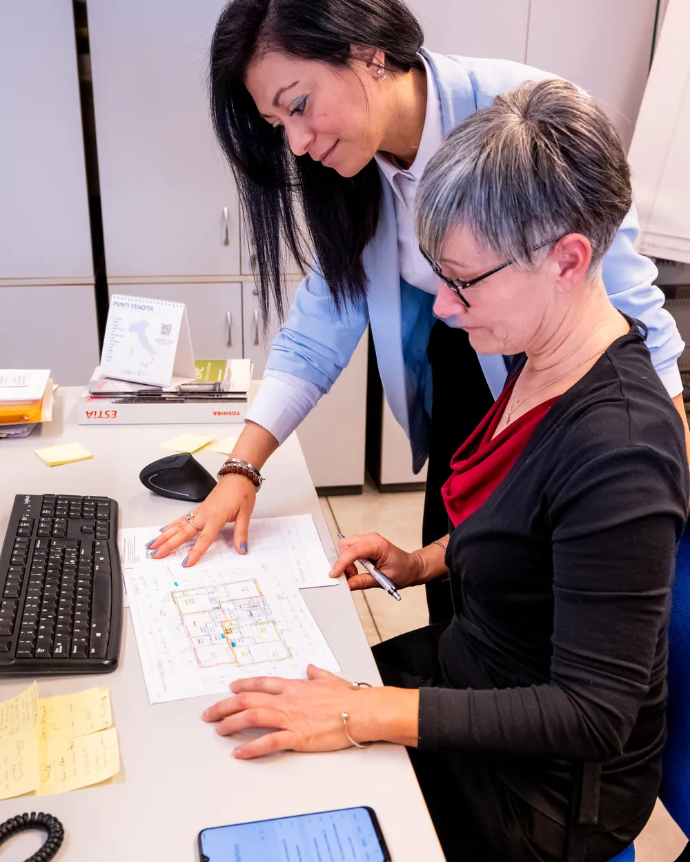 Silvia e Barbara nell'ufficio ErgonSì mentre preparano un progetto su una pianta della casa